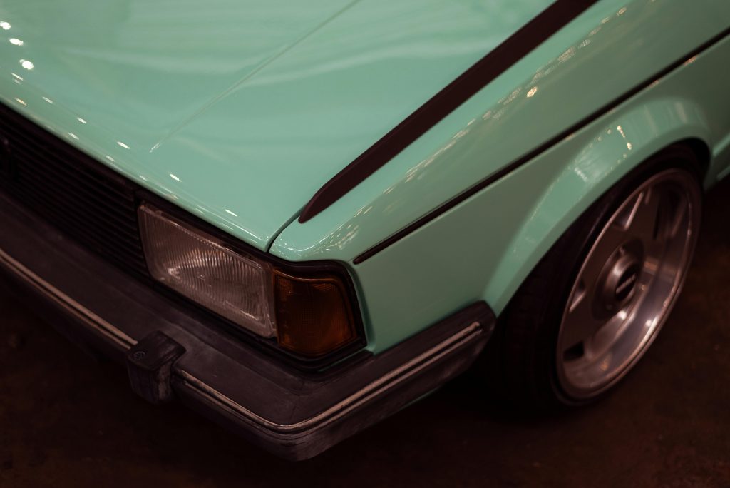 A detailed close-up of a vintage car's headlight and wheel with retro design.